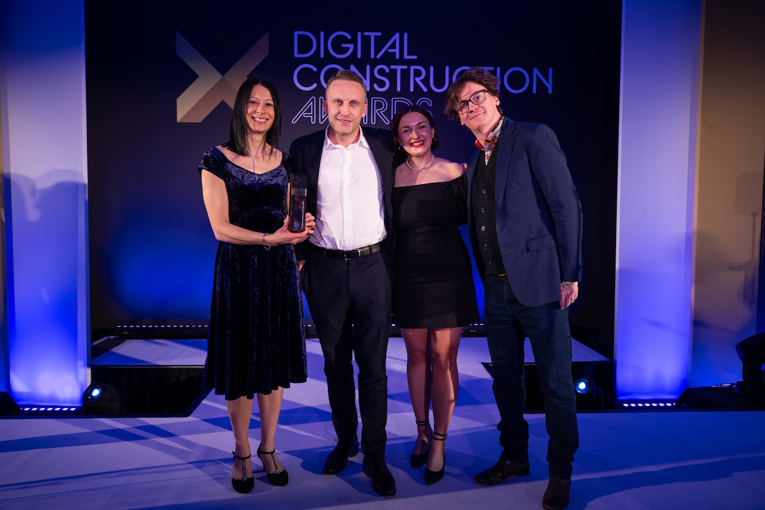 Harmony Fire collect their trophy from Ed Byrne (far right) and Karolina Orecchini of Digital Construction Week. Image: © 2026 - ASV Photography Ltd. www.ASVphotos.com